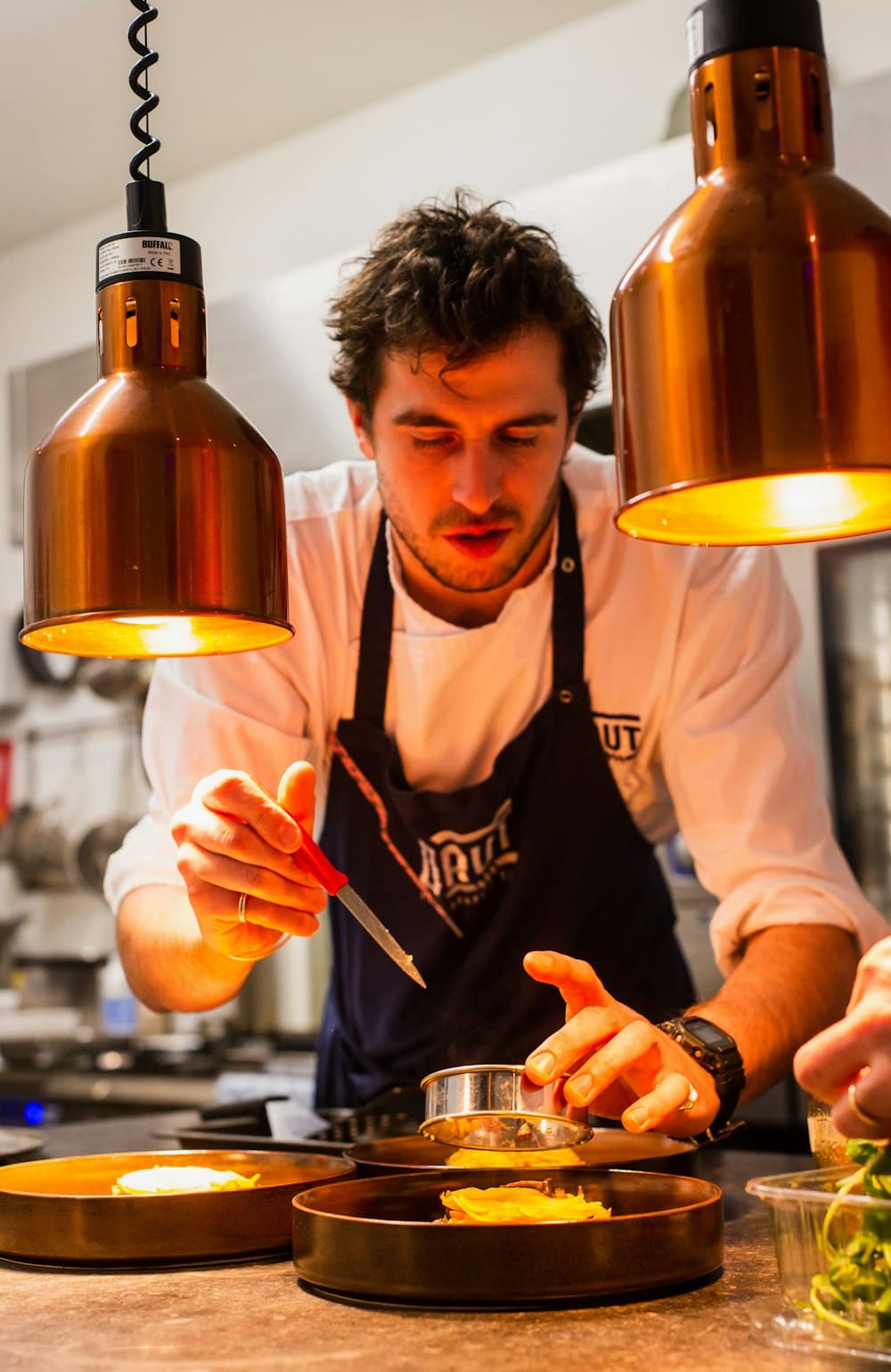 Portrait de Camille Lefranc, Chef de cuisine, en train de dresser une assiette